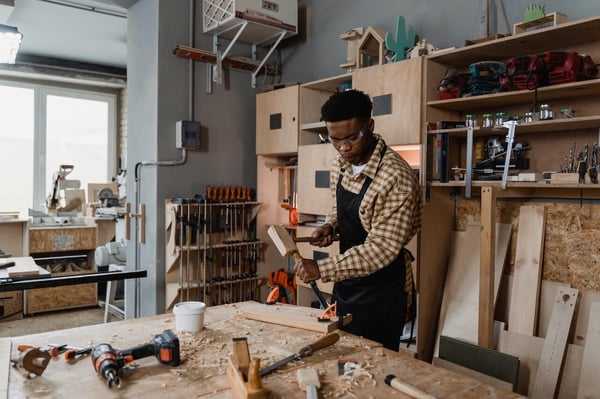 A person with ADHD is in a woodworking shop, and making precise measurements for their project.