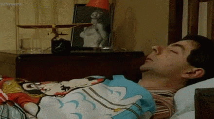 Mr. Bean GIF - an alarm clock is going off and he reaches over with his eyes closed to throw it in his glass of water.